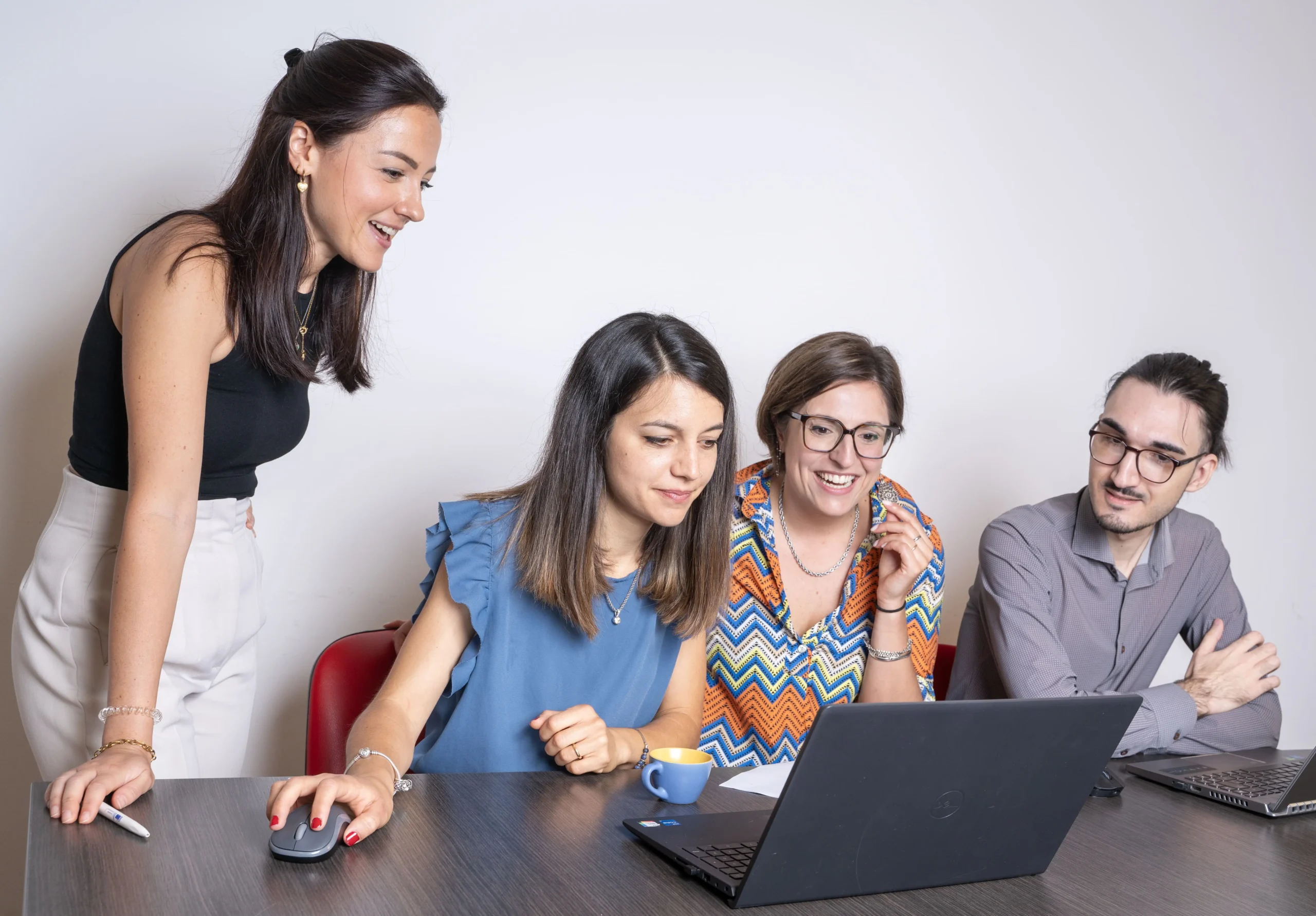 Quattro persone sono riunite attorno a un tavolo e stanno guardando un computer.